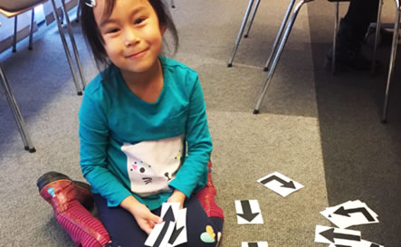 A girl sitting on floor with cut out arrows.